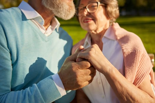 Closeup senior couple hand in hand together. Old man and woman giving love, support and empathy each other. Romantic date and walk for elderly people in public park