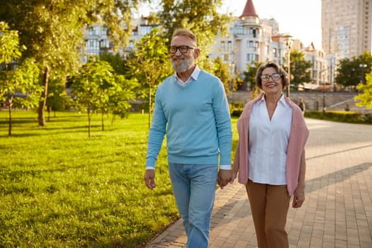 Happy senior couple tourist walking among public park on excursion enjoying fun time together and excited adventure in foreign country
