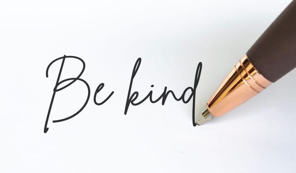 Be kind text written on white notepad.