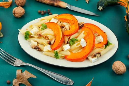 Appetizing autumn dish, pasta with baked pumpkins and nuts. Space for text.