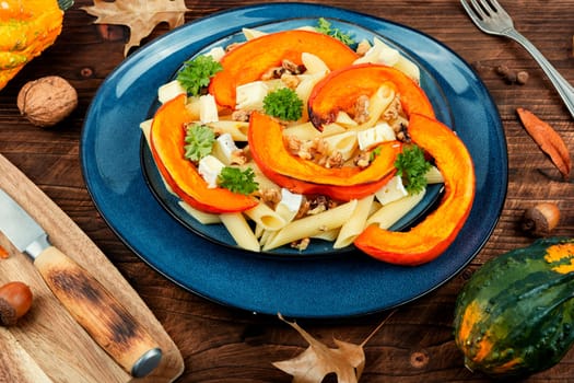 Appetizing autumn dish, pasta with baked pumpkins and nuts. Space for text.