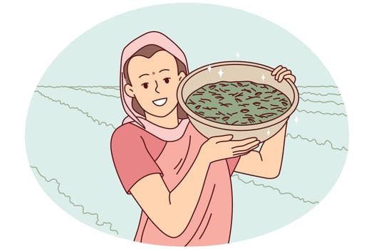 Smiling indian woman in traditional clothes show bowl working in field in countryside. Happy female worker collecting crop in rural grassland. Farming concept. Vector illustration.