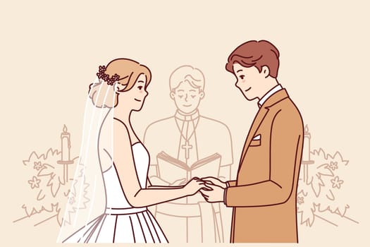 Bride and groom on altar, hold hands and listen to speech of priest during wedding ceremony