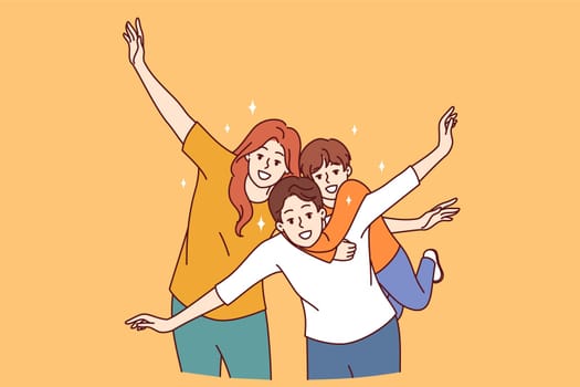 Happy family of mom, dad and child put arms to sides, pretending to be airplanes, and posing for group portrait. Cheerful family having fun and smiling looking at camera to share good mood