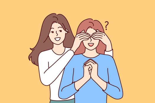 Happy woman closes sisters eyes, coming up from behind and making surprise, asking riddle who it is. Young female friends doing surprise when meeting and getting pleasant emotions from communication