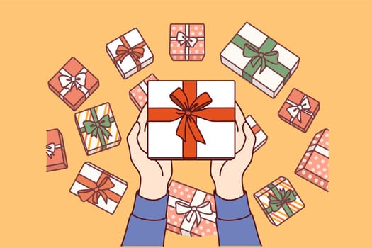 Gift box wrapped in red ribbon and bow in hands of man demonstrating packaging options for holiday present. Gift box for congratulating friend on birthday or giving to regular store customer