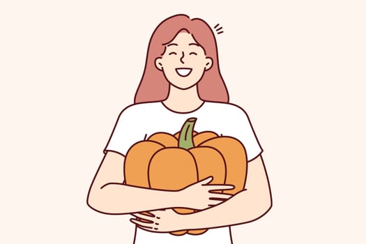 Girl hugs pumpkin and smiles widely, rejoicing at good harvest and opportunity to make jack-o-lantern for halloween holiday. Happy woman with pumpkin in hands laughing preparing for thanksgiving