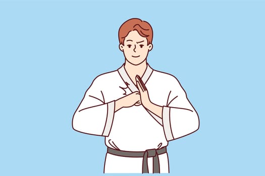 Man fighter in karate or taekwondo clothes makes welcoming gesture to invite opponent to start fight. Guy is interested in karate and studying self-defense techniques to maintain sports lifestyle