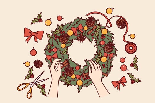 Diy christmas wreath made from green fir branches and red bows or pine cones for interior decoration. Process of making christmas wine to prepare for new year holidays or xmas eve.