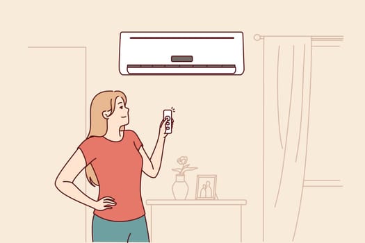 Woman turns on air conditioner standing in living room and uses remote control to set comfortable temperature. Happy girl rejoices at presence of modern air conditioner to combat summer heat
