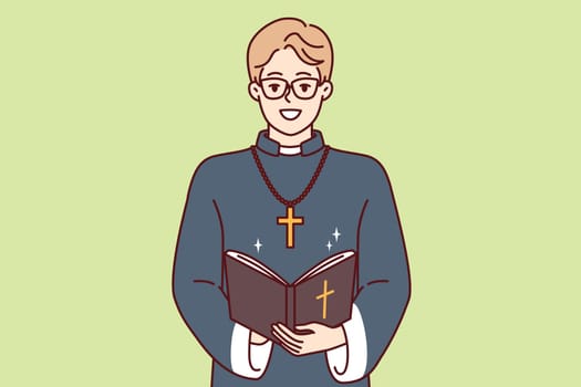 Happy man priest with bible and golden cross on neck smiles preaching and reading prayers in christian church. Young priestly mentor monastery or catholic cathedral teaches religious texts