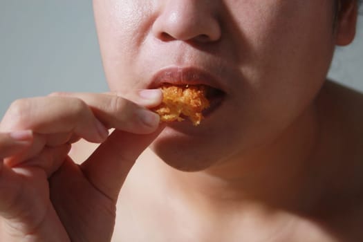 Woman happily eating sausage on gray blurred background