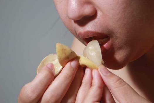 Woman eating Langsat, Longkong, is a fruit found in the forests of tropical countries in Asia. And it is a fruit with a delicious aroma that is popular in Thailand, Malaysia, Singapore, Indonesia, Laos and Vietnam