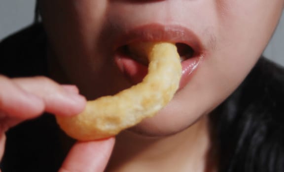 Woman eating crispy pastries, It is a popular street food that is delicious and commonly found in Asian countries such as Thailand, China, Laos, Vietnam, and Burma.