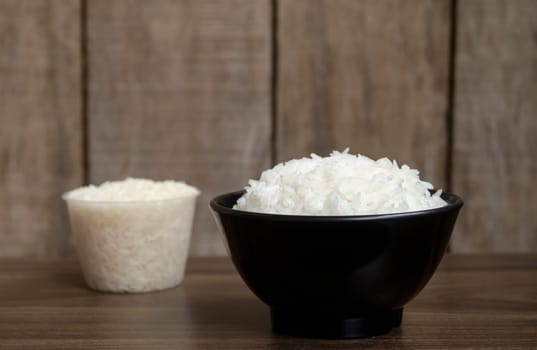 Rice in cup on wooden table blurred background