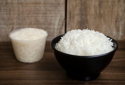 Rice in cup on wooden table blurred background
