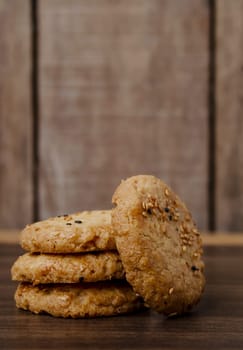 Cookies are stacked on a wooden board with a soft blurred background.