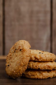 Cookies are stacked on a wooden board with a soft blurred background.