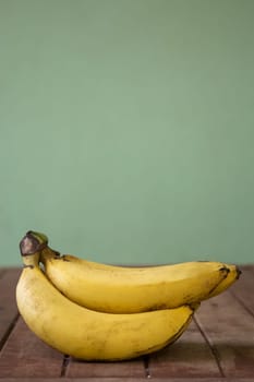 Banana fruit with wooden table on blurred green background