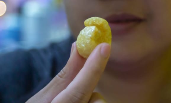 Woman is holding crispy pork rinds that she is about to eat. It is a popular street food that is delicious and commonly found in Asian countries such as Thailand, China, Laos, Vietnam, and Burma.
