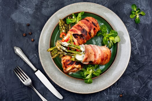 Baked roulades wrapped in bacon. Meat stuffed with asparagus on a plate.