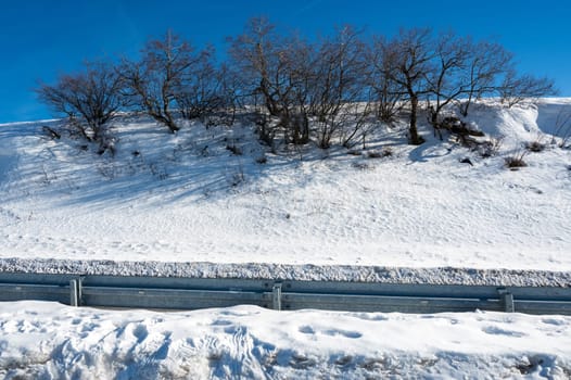 Winter landscape with trees, road , lots of snow and blue sky in the high Rhoen, Hesse, Germany
