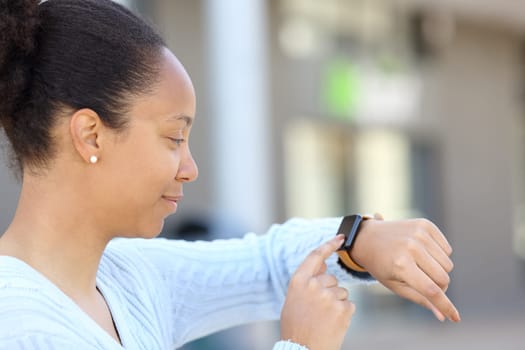 Black woman checking smartwatch outdoors in the street