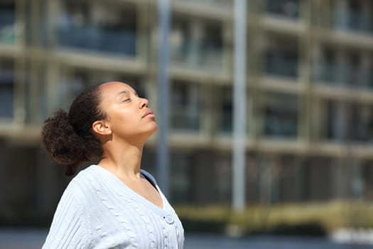 Serious black woman breathing fresh air in the street