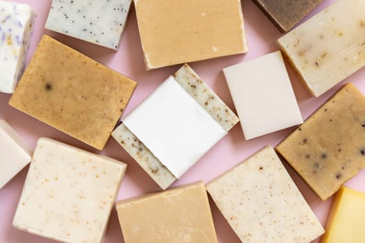 Beige and brown handmade soap bars on light pink top view, soap packaging mockup, copy space. Natural herbal products for for face and body care. Using organic handmade skincare products