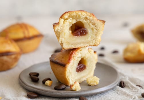 Pasticciotto leccese pastry filled with egg custard cream and sour cherry jam. Whole and half pasticiotties on a plate served for typical apulian breakfast, close up. Table decorated with coffee beans