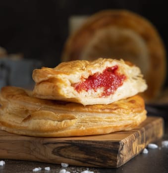 Rustico traditional puff pastry stuffed with bechamel sauce, tomato and mozzarella cheese, close up on a dark table. Traditional street food from Salento, Lecce, Italy