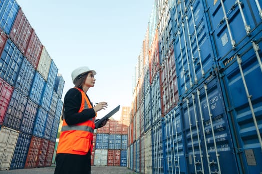 Woman engineer with Clip Folder in white helmet and vest working in container terminal port.