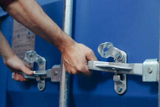 Close up view on man hands is opening the lock of large shipping container doors.