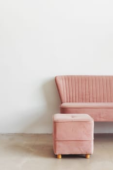 Minimalist composition of room interior with pink pouf and sofa against white wall, copy space.