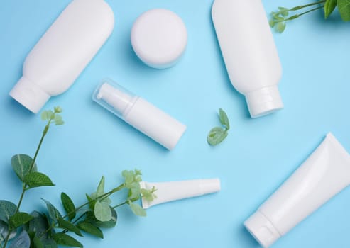 White plastic tubes, jars, and containers for cosmetic products on a blue background, advertising and branding of products