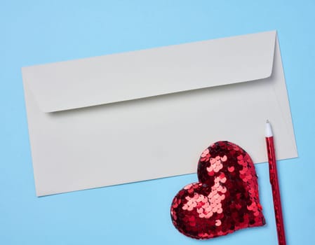 White envelope, red heart on a blue background, top view