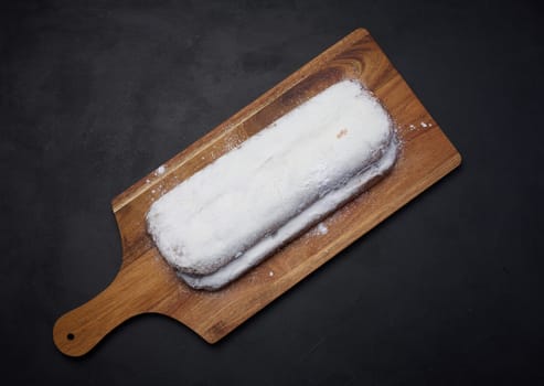 Christmas pastries stollen sprinkled with powdered sugar on the table, festive dessert, top view