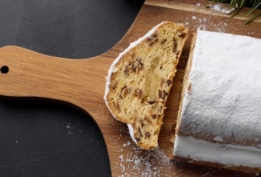 Christmas pastries stollen sprinkled with powdered sugar on the table, festive dessert. Top view