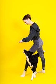 Shot of sport female in leggings with a border collie dog isolated on yellow and red background