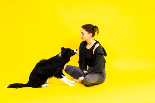 Shot of sport female in leggings with a border collie dog isolated on yellow and red background