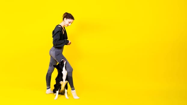 Shot of sport female in leggings with a border collie dog isolated on yellow and red background