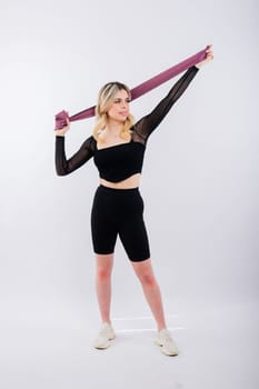 Young woman workout with resistance band on a white background. Strength and motivation.