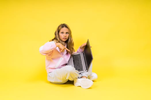 Fitness online. Girl doing stretching exercise on a floor alone with laptop at studio