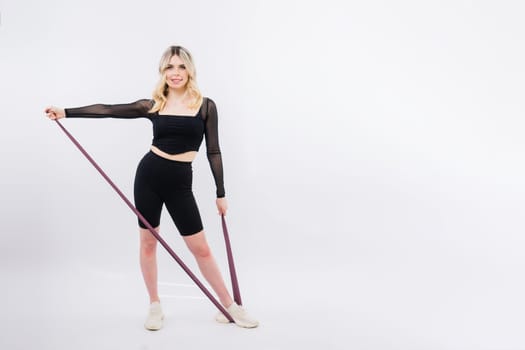 Young woman workout with resistance band on a white background. Strength and motivation.
