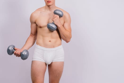 Shirtless bodybuilder holding a dumbell and showing his muscular arms.