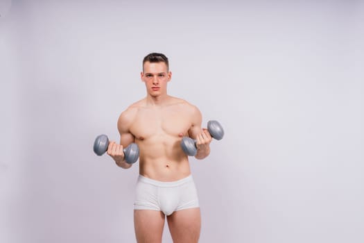Shirtless bodybuilder holding a dumbell and showing his muscular arms.