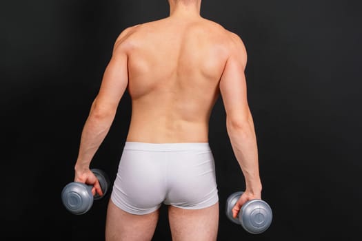 Shirtless bodybuilder holding a dumbell and showing his muscular arms.