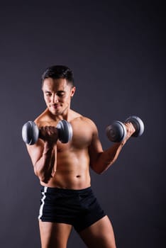 Shirtless bodybuilder showing his great body and holding dumbells.