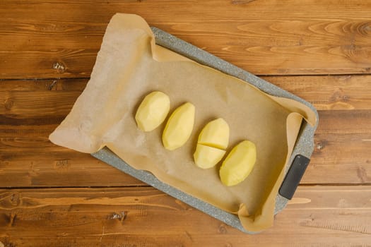 Top view of sliced hasselback potato on a parchment in baking tray