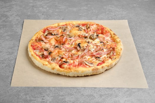 Pizza with ham and champignon mushrooms on parchment